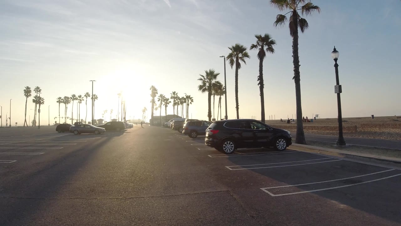 Wide parking lot view with palms and sunrise over the beach side.