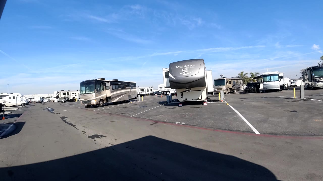 The vehicle perspective shifts across the Huntington Beach RV lot, showing motor homes, open asphalt, lane markings, and no visible people.