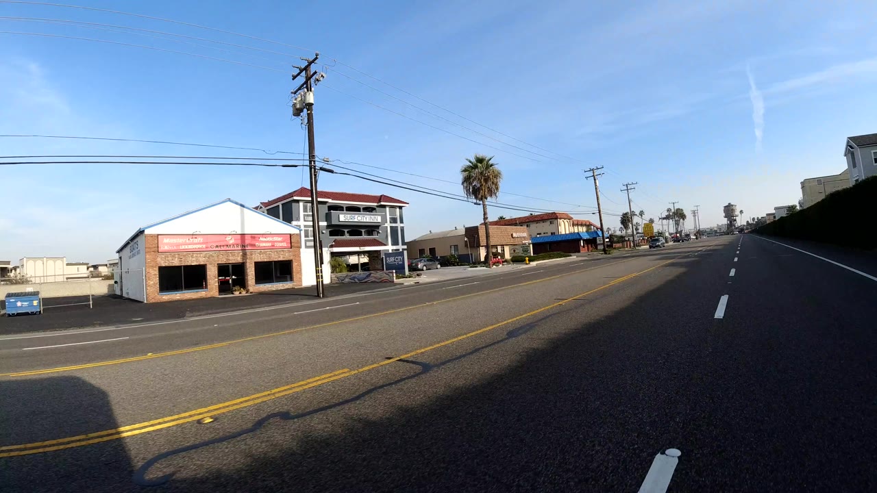 Commercial roadside block with storefronts, power lines, and traffic lanes