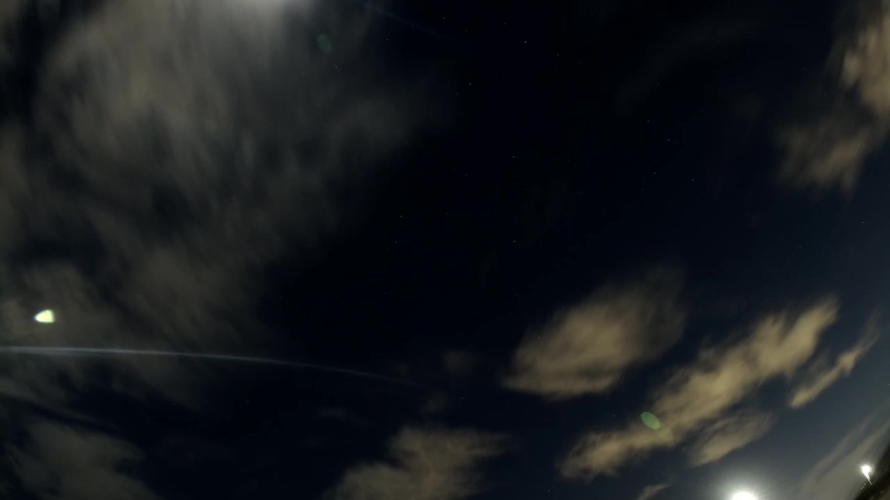 Dark sky with blurred clouds and small bright lights.