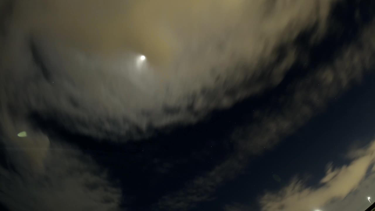 Thick pale clouds dominate the upper Bolsa Chica, California sky while sun glare shows through the darker area, with no visible people.