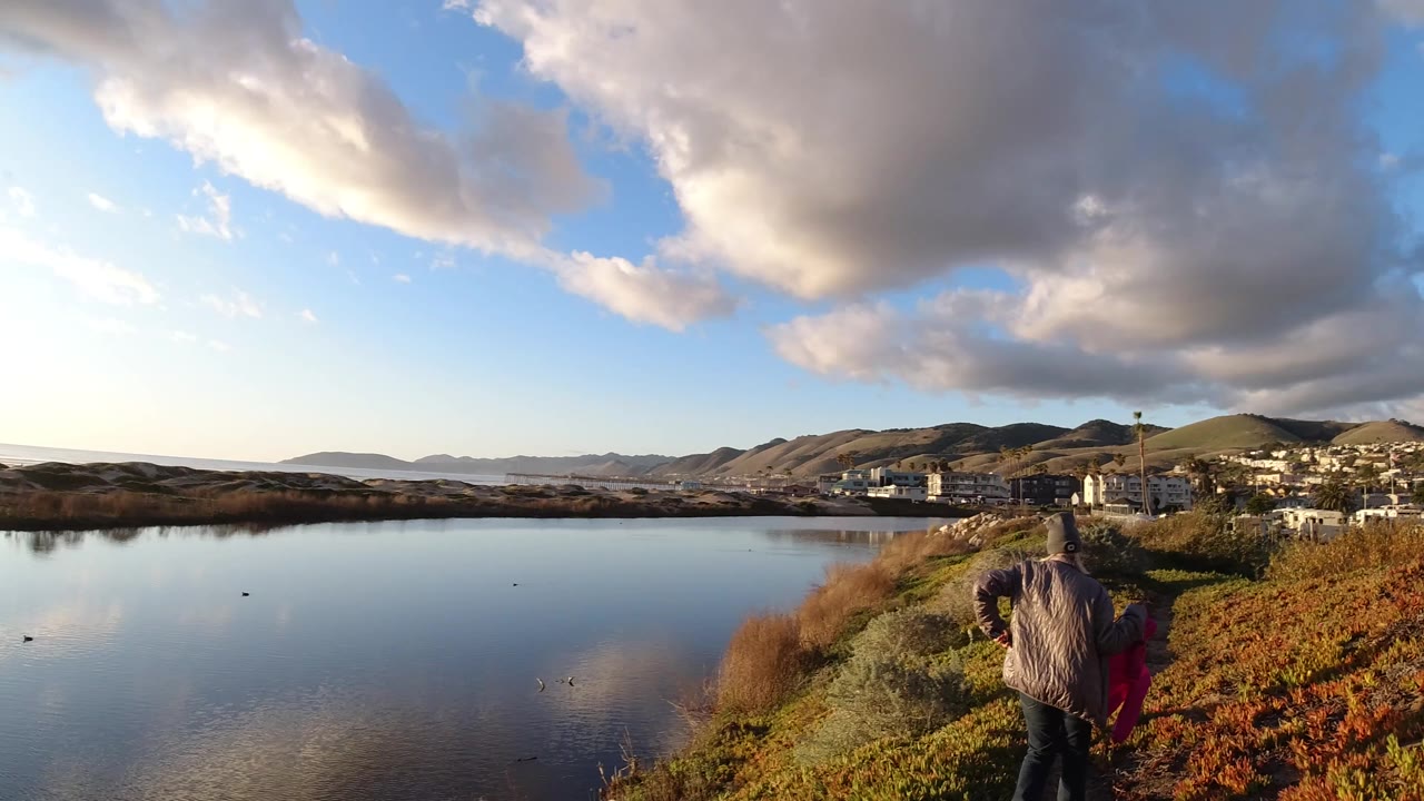 Wide riverside view with a person walking away from camera.