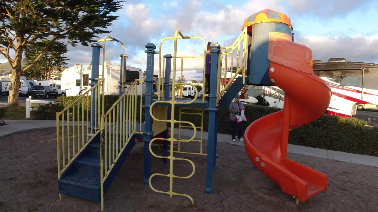 Orange slide and yellow railings with a child partly hidden on the playground.
