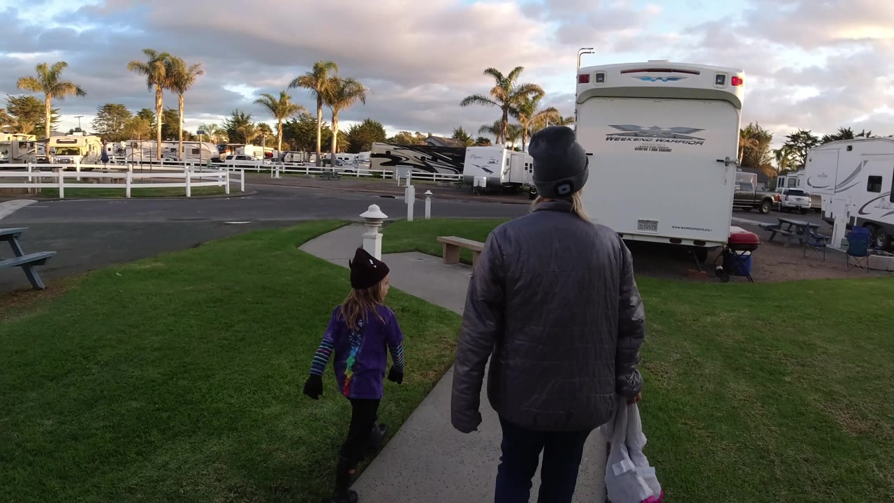 Woman and child walking between grass and RV parking