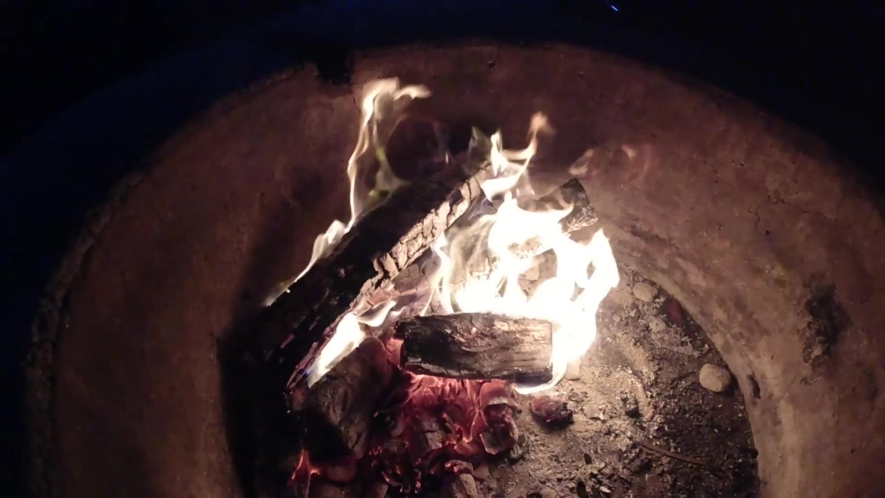 At 0:03, the fire burns brightest near the center of the rounded basin, lighting the ash and inner wall in Pismo Beach, California, with no visible people.