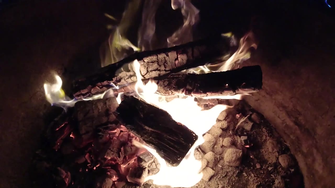 At 0:03, the Pismo Beach fire sits lower across the frame, with charred firewood over glowing coals and no visible people.