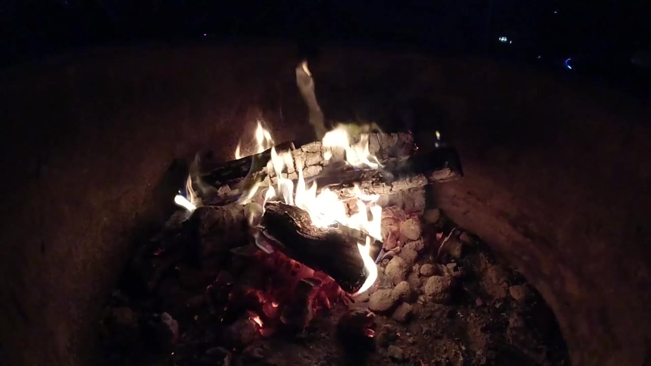 At 0:00, burning logs glow inside a dark container in Pismo Beach, California, with bright flames and no visible people.