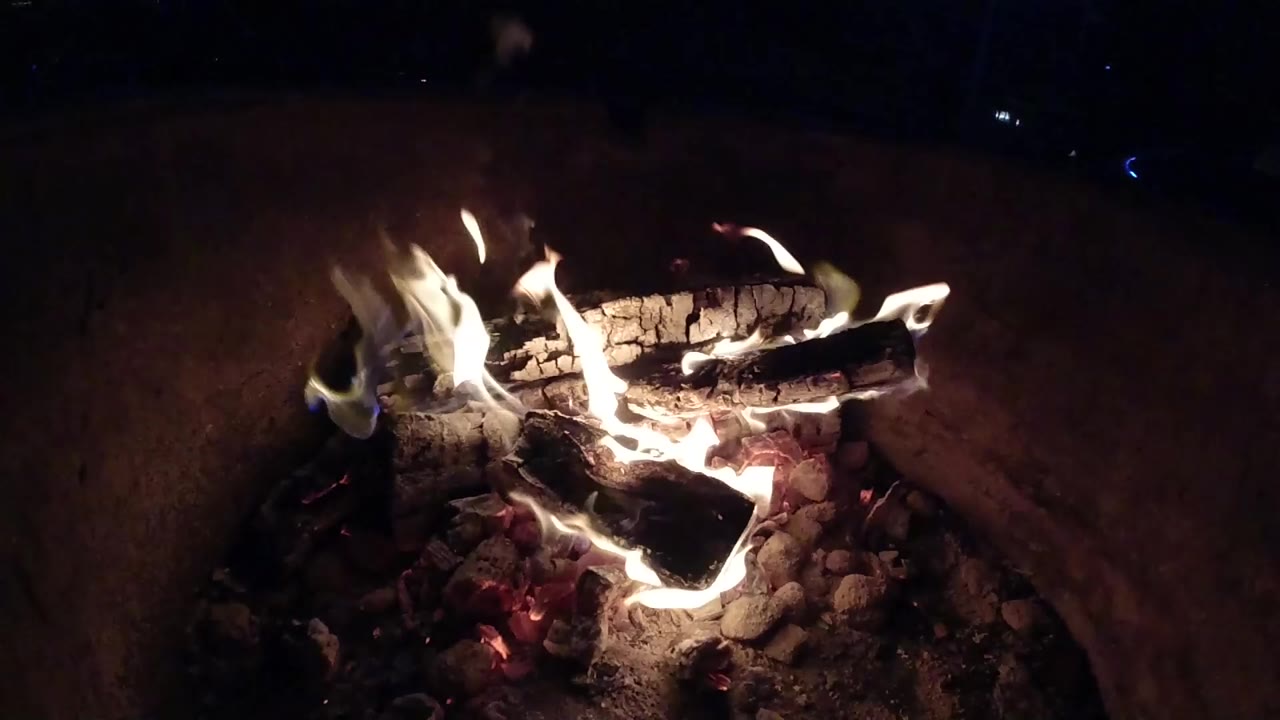 At 0:00, a Pismo Beach campfire burns on stacked logs inside a rock ring on sand, with no visible people.