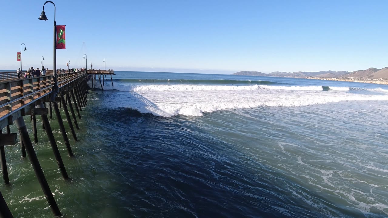Foamy wave reaches across the water near the pier.