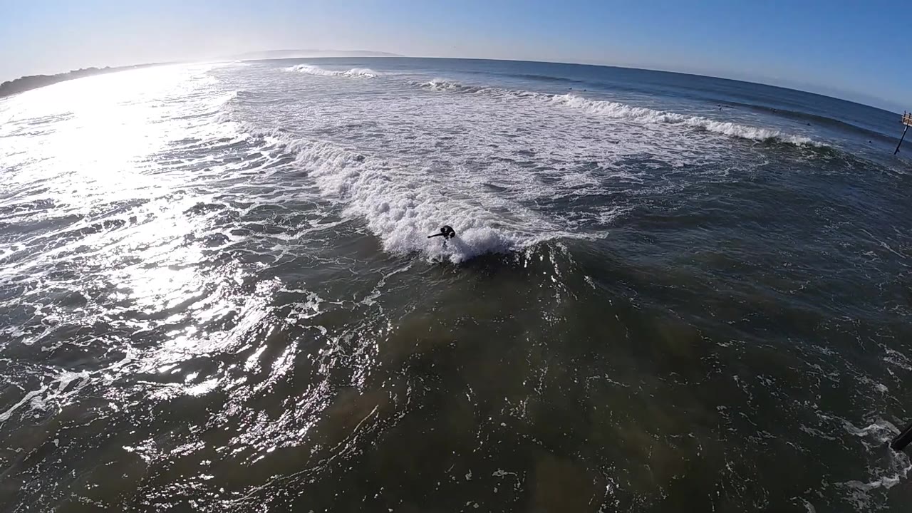 At Pismo Beach, California, the surfer shifts toward the right side of the wave, with a white spray patch around the board and darker open water in the foreground.