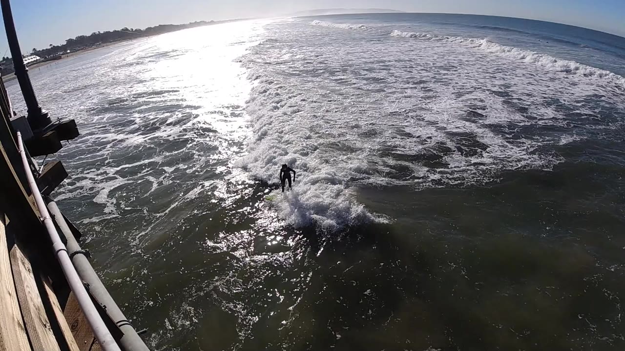 Lone surfer riding toward foamy breaking water.