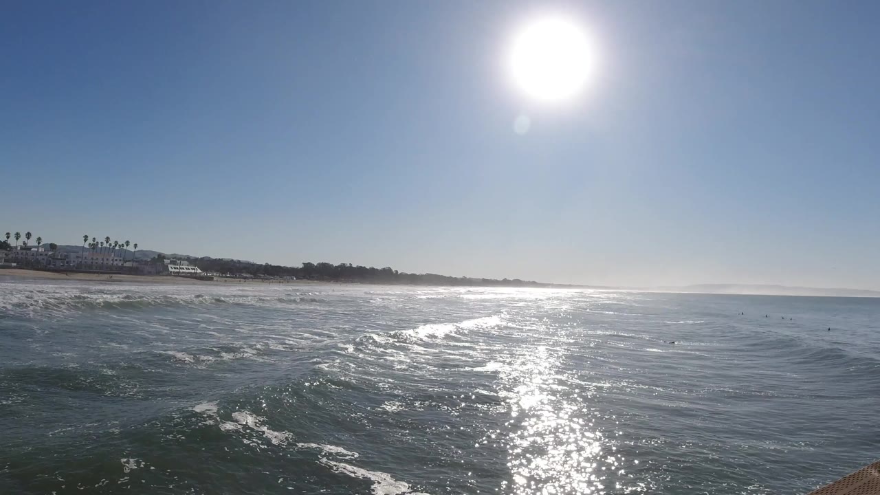 Ocean surface with sun glare and distant shoreline.