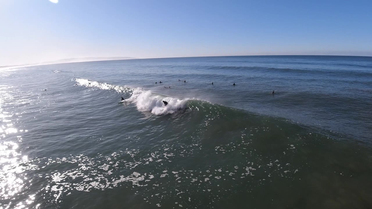 Surfer rides beside thick whitewater on a sunlit wave.