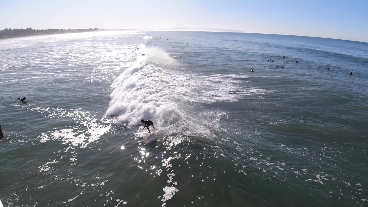 Surfer rides whitewater while other surfers wait offshore.