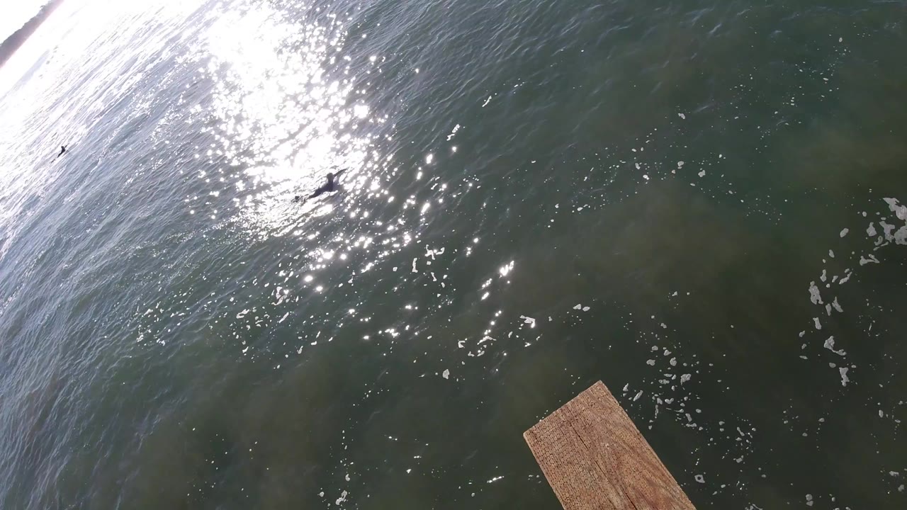 Sun sparkles on rippling water with a wooden platform corner below.