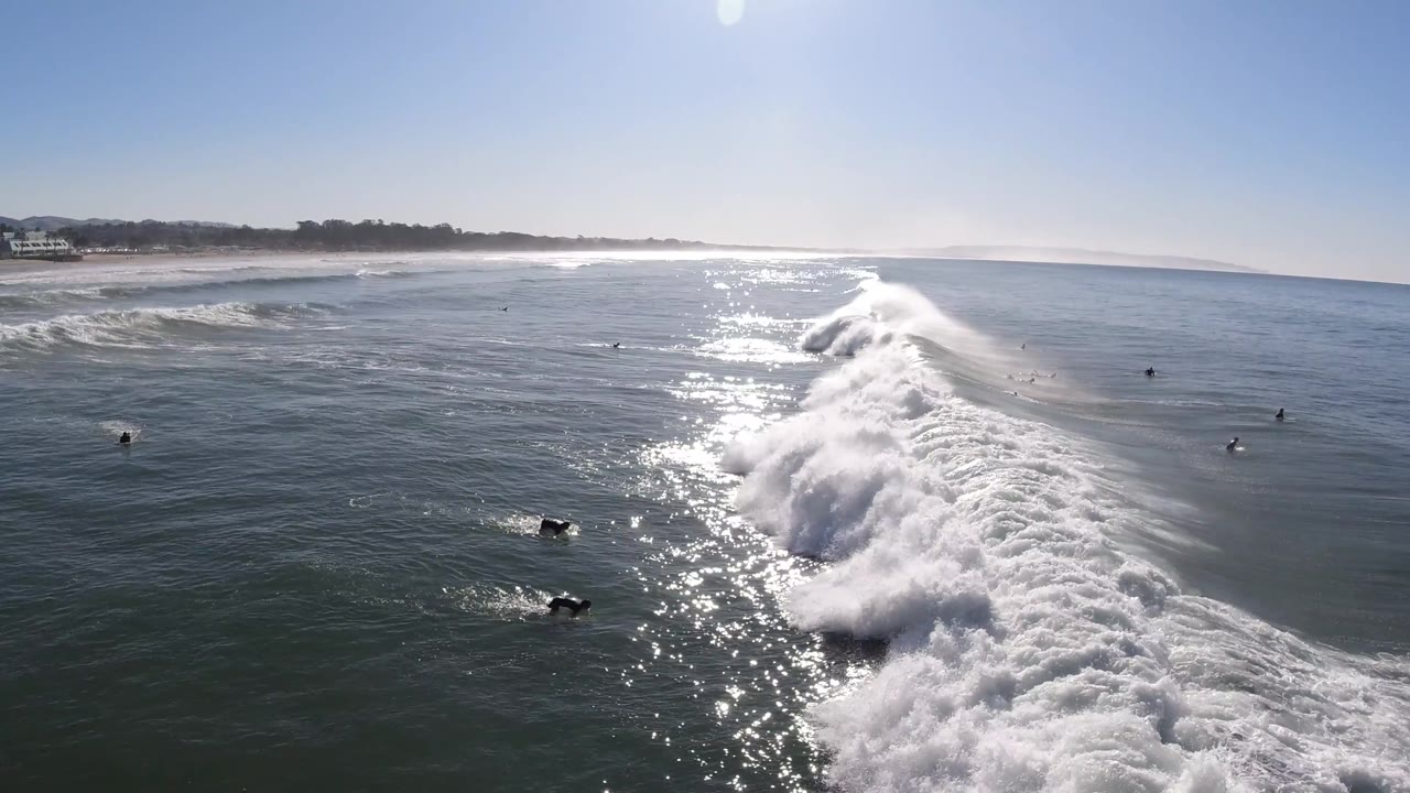 Long white surf break running toward shore with beach in the background.