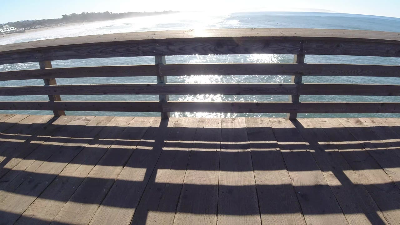 Angled pier railing over ocean with beach behind