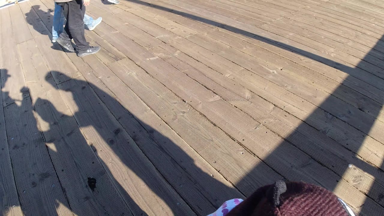 Child partly cropped at bottom of a sunlit wooden deck.