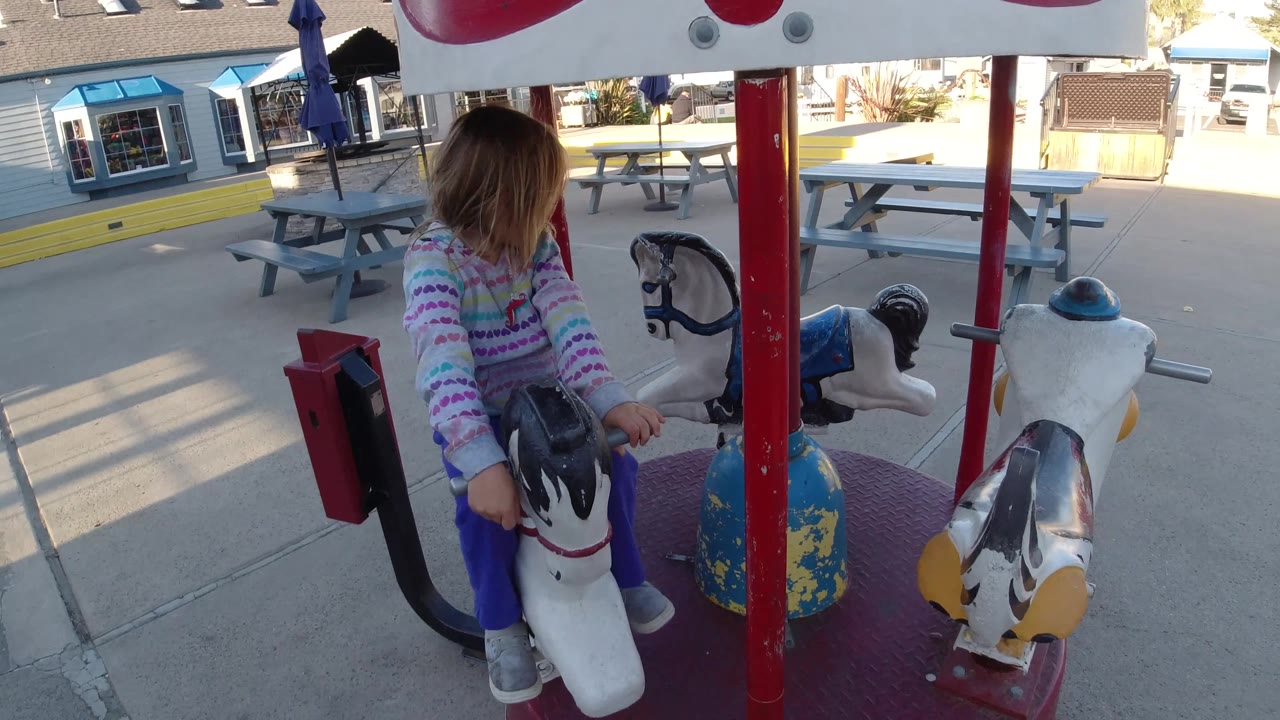 Child seen from the side on a small carousel horse.