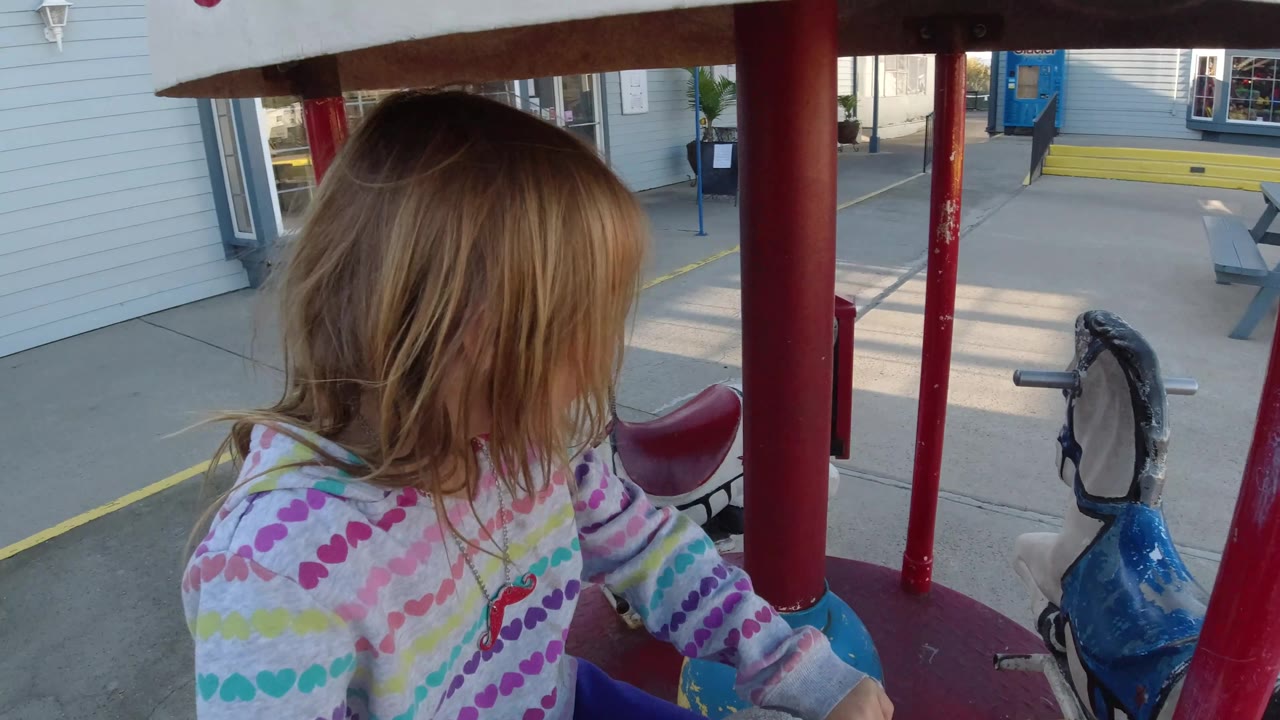 Close side view of a girl on a small carousel ride.