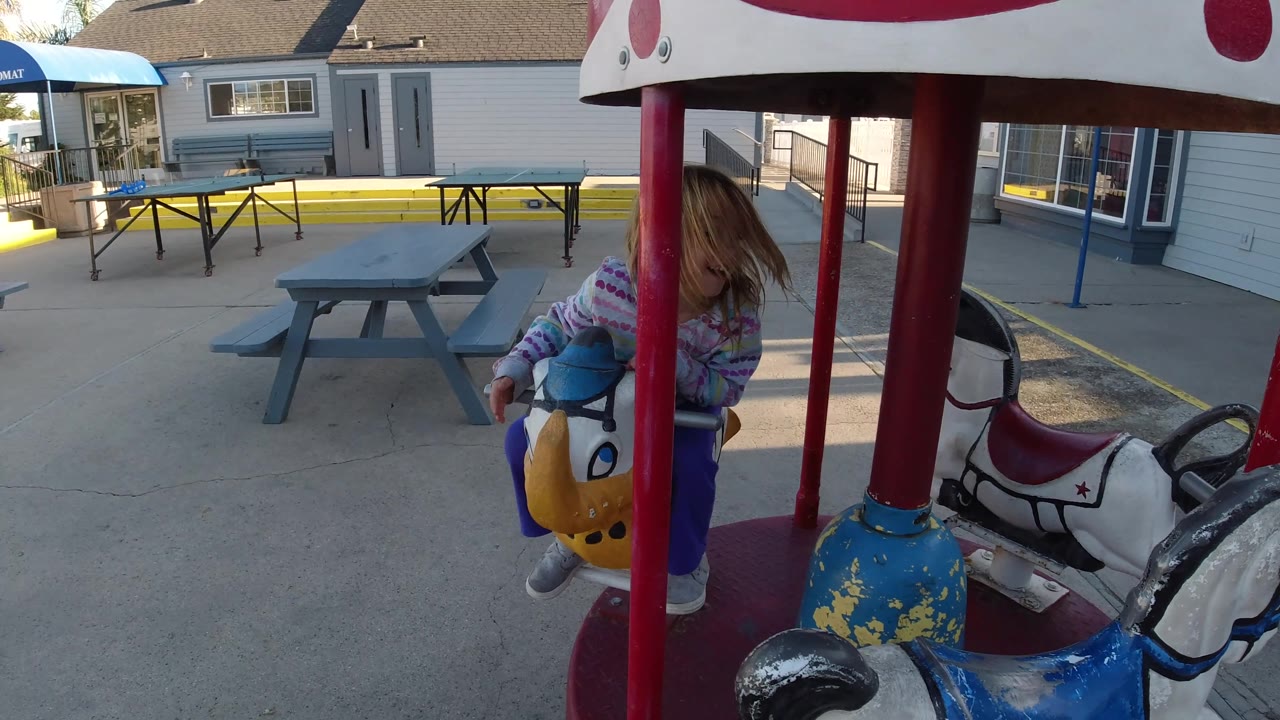 Girl riding past the camera on a carousel horse.