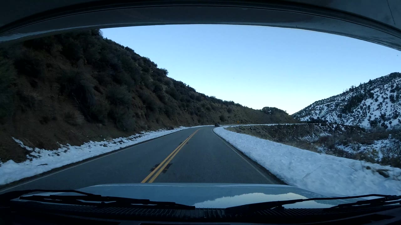 Empty mountain road with snow piled along both shoulders.