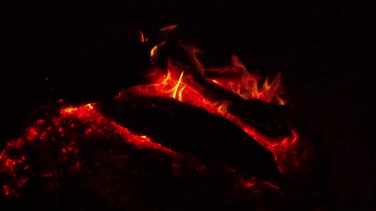 At 0:01, small orange flames lift from the top edge of a glowing charred log in Ojai, California, with no visible people.