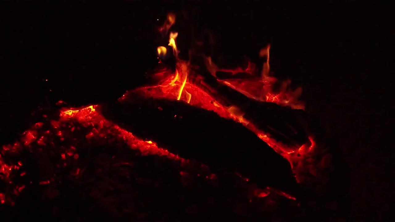 At 0:03, the Ojai fire detail shifts to a lower flame leaning over the charred log while red coals remain visible underneath, with no visible people.