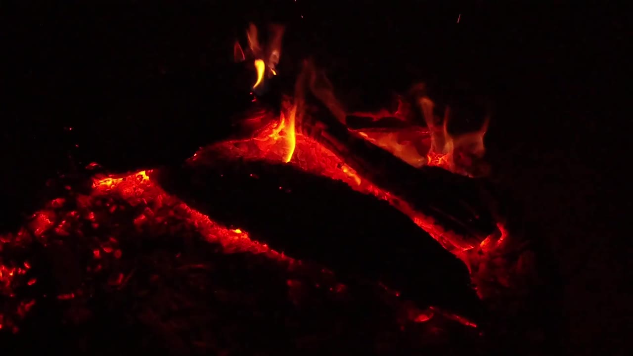At 0:03 in Ojai, California, a brighter vertical flame appears near the left side of the log while red coals glow below and no visible people are present.