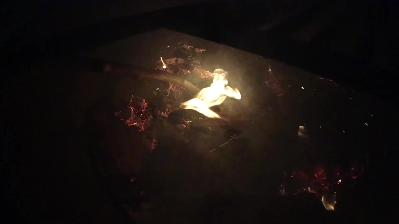 Bright flame burns over red embers in a mostly black Ojai, California fire detail, with no visible people.