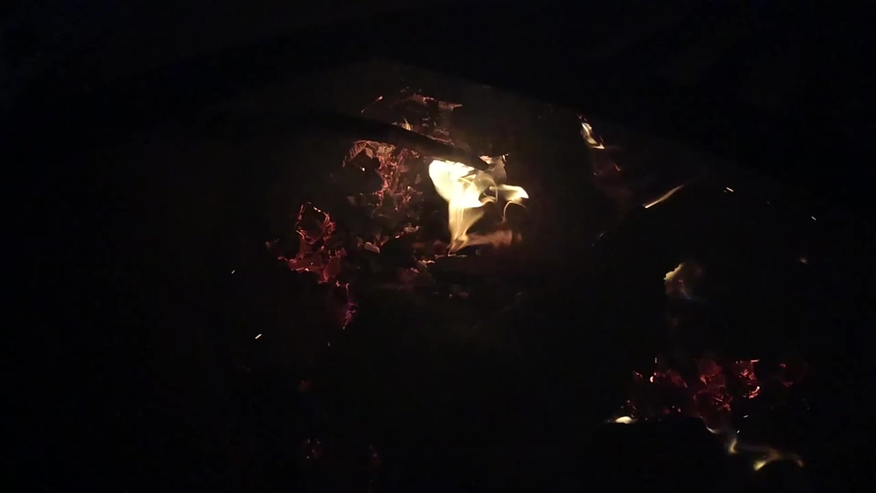 At 0:00, small yellow flames burn over dark logs and red embers in Ojai, California, with no visible people.