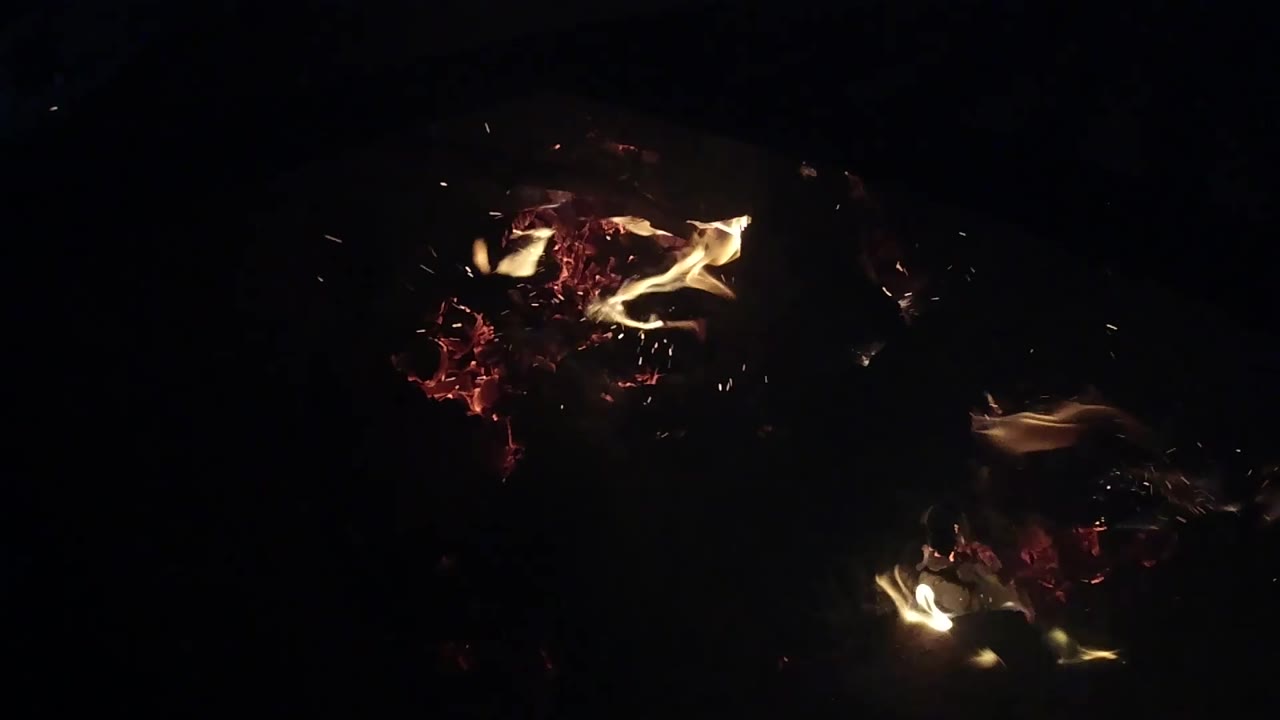 Glowing embers and small flames with scattered sparks.