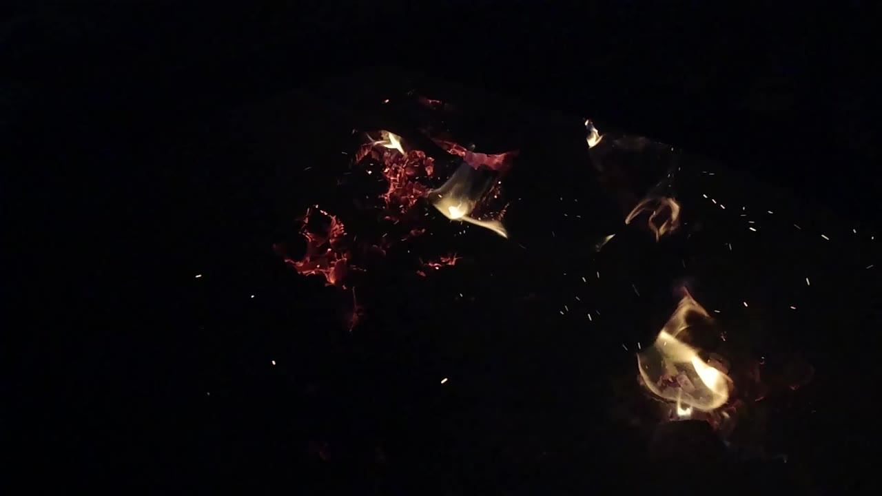Glowing ember cluster with flame pockets on black background