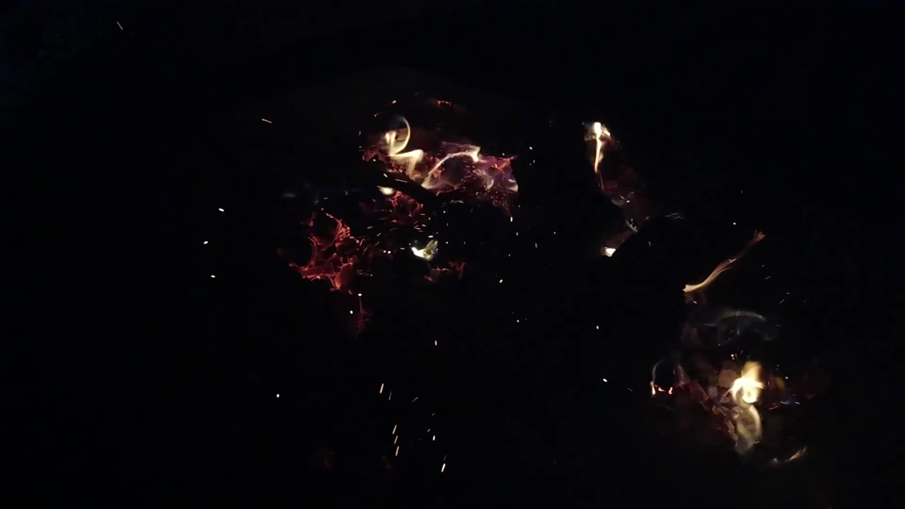 At 0:02, two separated clusters of fire glow in the dark frame, with red embers on the left and brighter flame on the right, and no visible people.