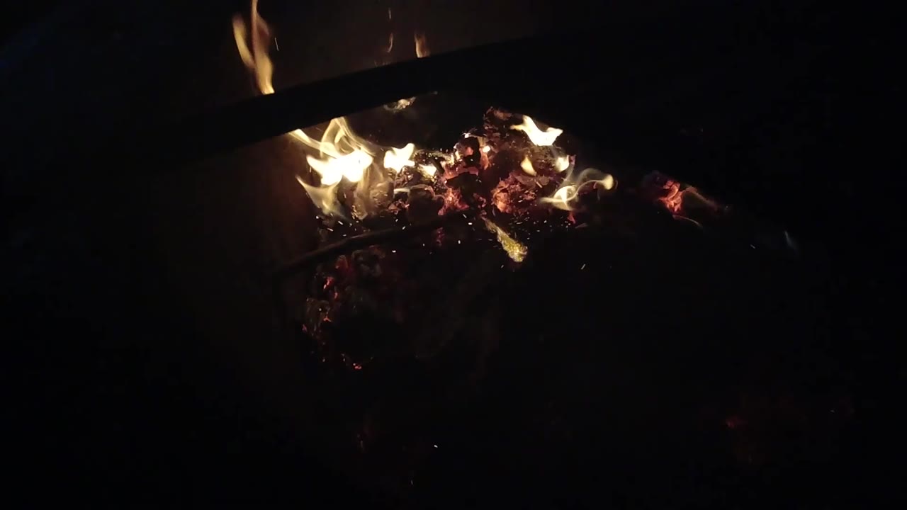 At 0:02, the flames sit slightly farther right in the dark Ojai frame, with glowing embers below and a black diagonal object cutting across the upper fire area.