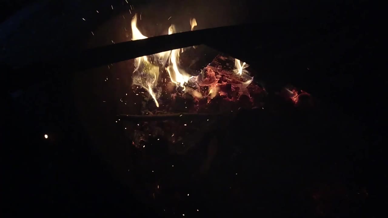 Flames flare over red embers in Ojai, California, with a dark bar cutting across the upper fire area and no visible people.