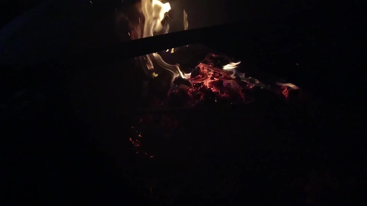 At 0:01, the flame cluster sits higher in the frame over red embers in the Ojai nighttime fire, with most of the surrounding image falling to black and no visible people.