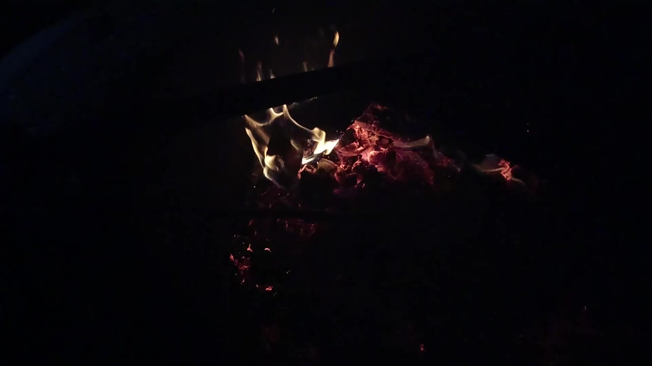 At 0:01, the flame cluster sits higher over the ember bed in Ojai, California, while most of the surrounding frame remains black and no visible people appear.