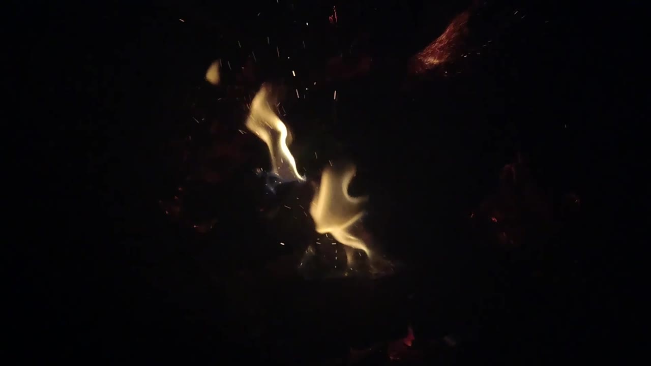 Two pale yellow flame shapes appear on the right side of the Ojai, California fire frame with dim embers behind them and no visible people.