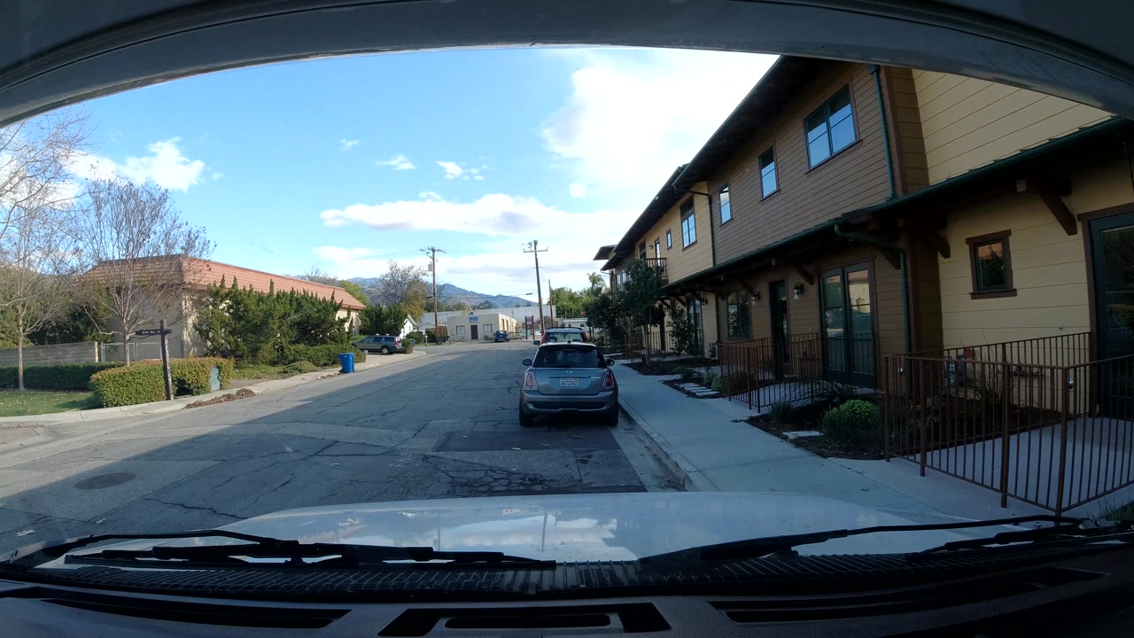Third frame shows the same Ojai, California street view from inside the vehicle, with the parked car slightly right of center, shaded building overhang on the right, open sky above, and no visible people.