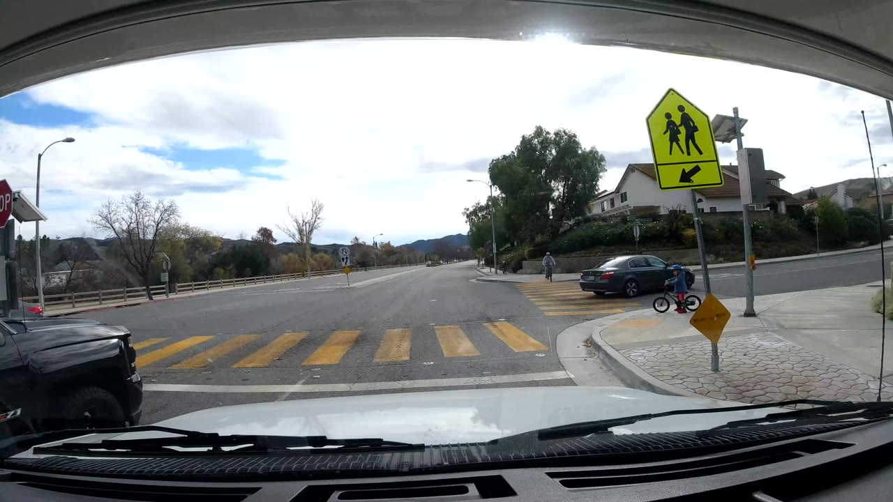 Dashcam view of the same crosswalk and school crossing sign from a slightly advanced position.