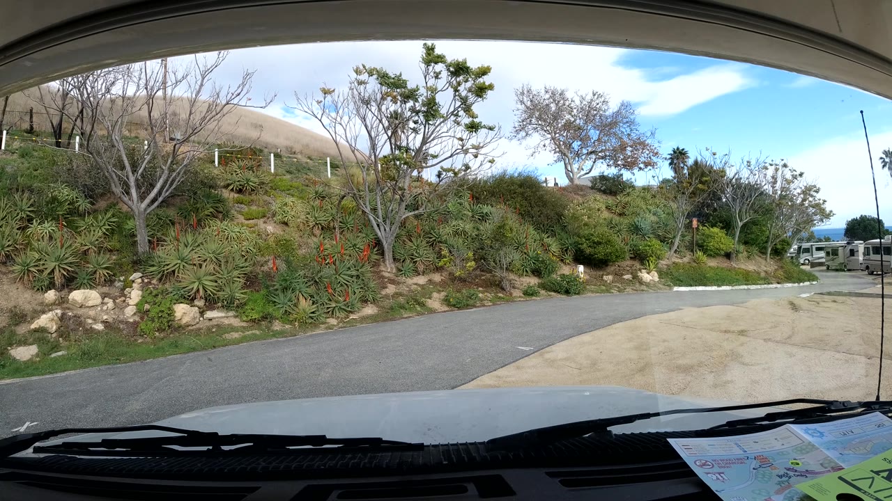 Roadside hillside seen through a windshield with dashboard and wipers in foreground.