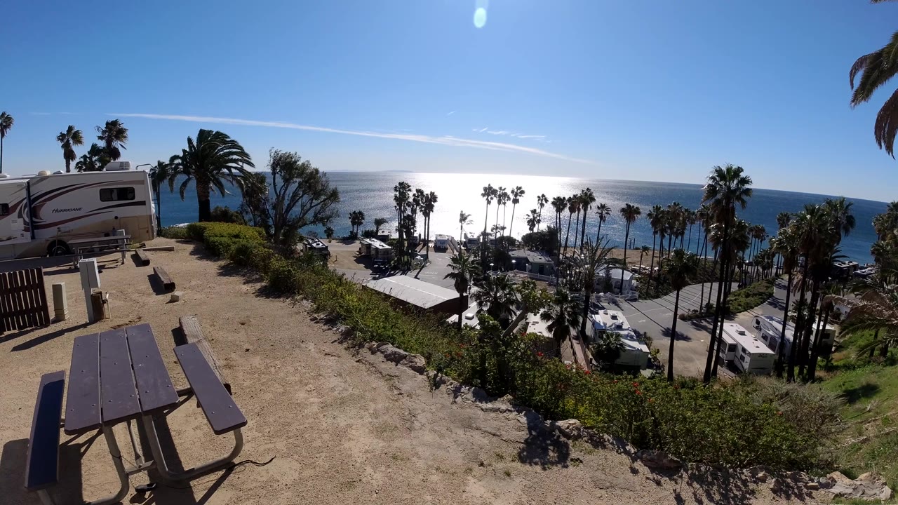 Beach overlook with picnic table in shade and sun reflecting across the ocean.