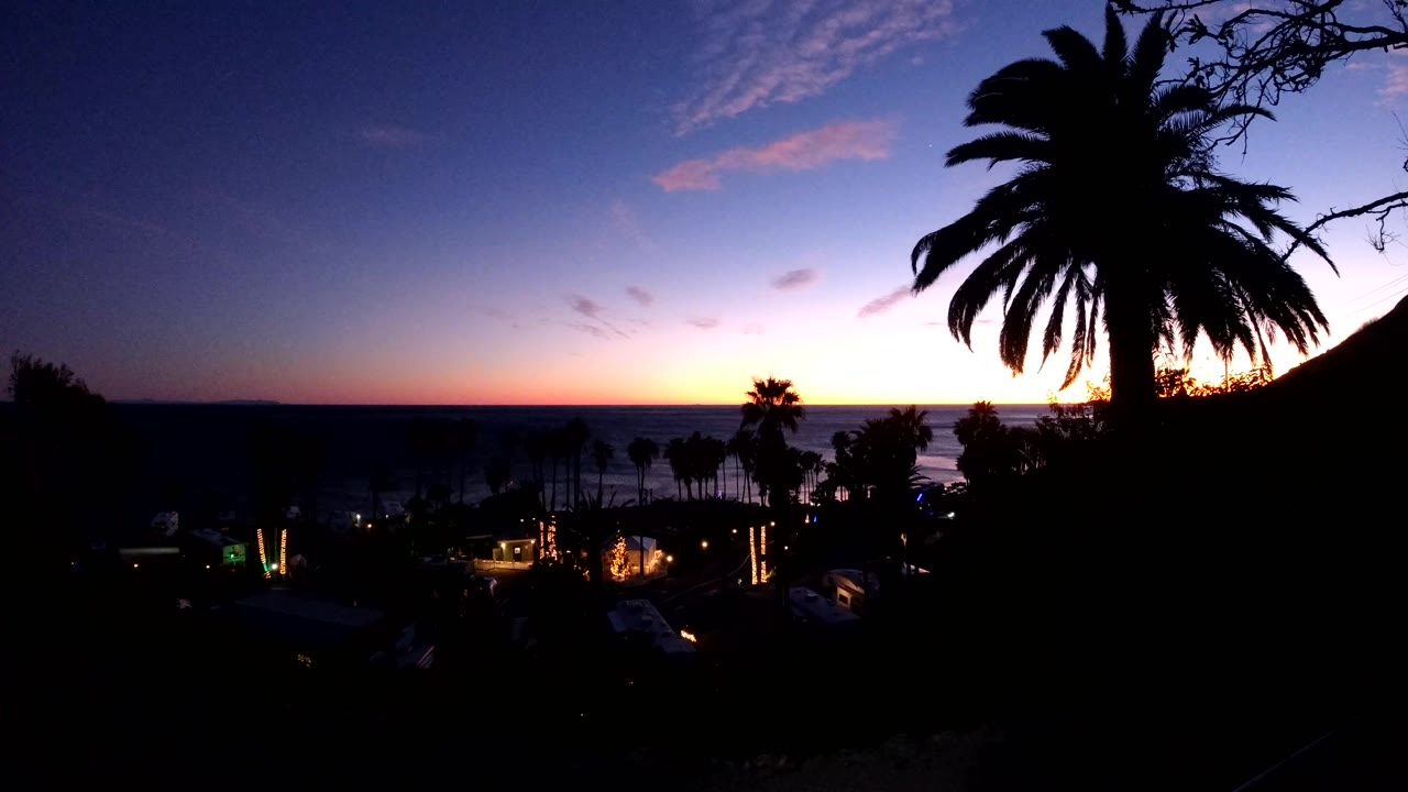Fourth frame shows a slightly darker Malibu overlook, with clustered palms below, a low ocean horizon, orange light near the horizon, and no visible people.