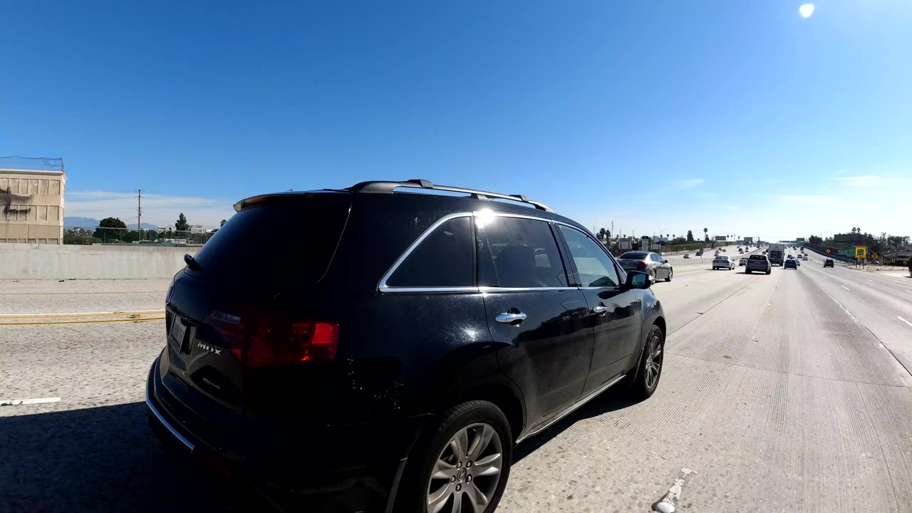 Black SUV near camera on bright multilane freeway with distant traffic.