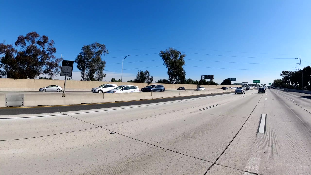 Open freeway lanes with traffic across a concrete divider.