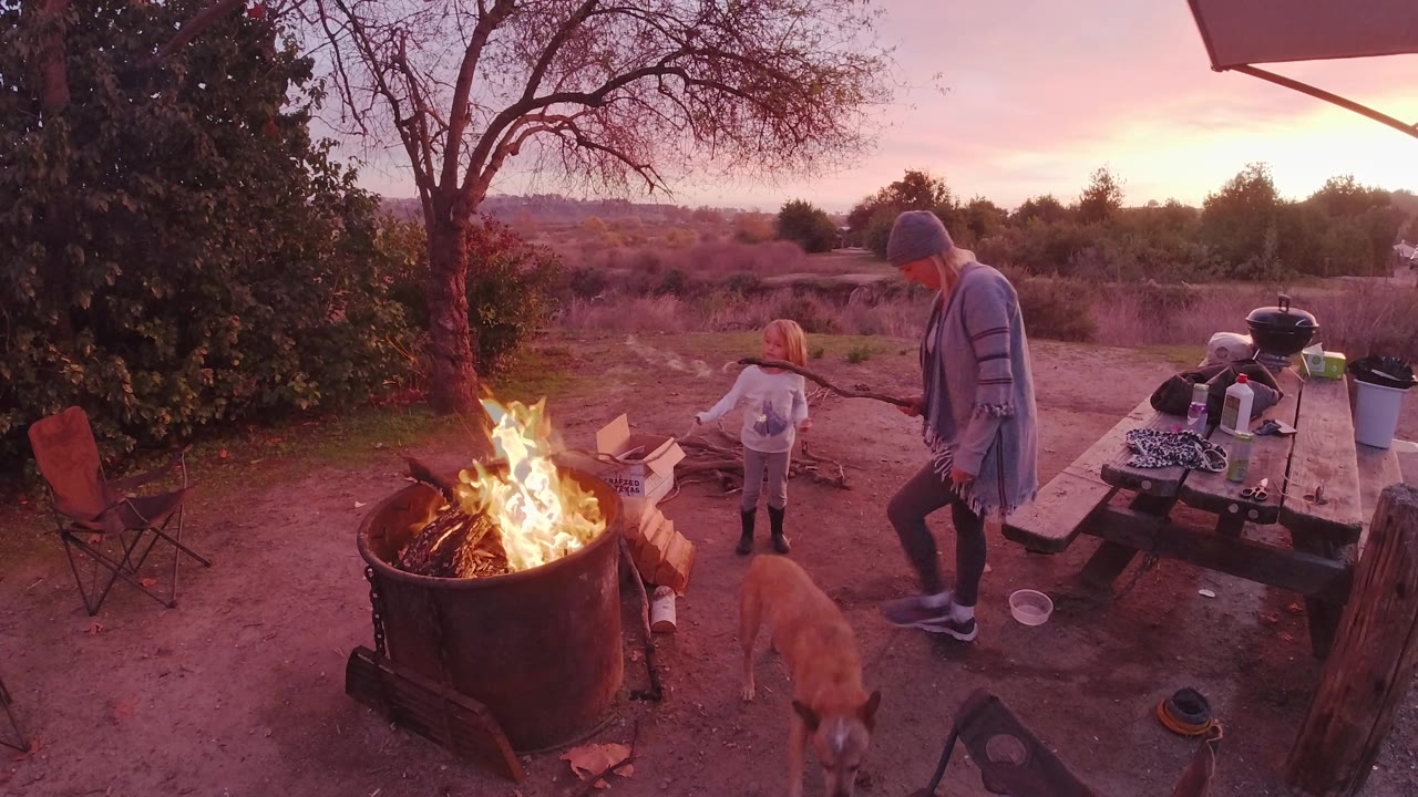 In San Clemente, California, the older woman and child stand to the right of the fire pit while the tan dog faces them near the center of the frame.