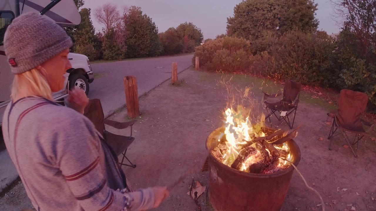 Person near campfire with white van parked behind