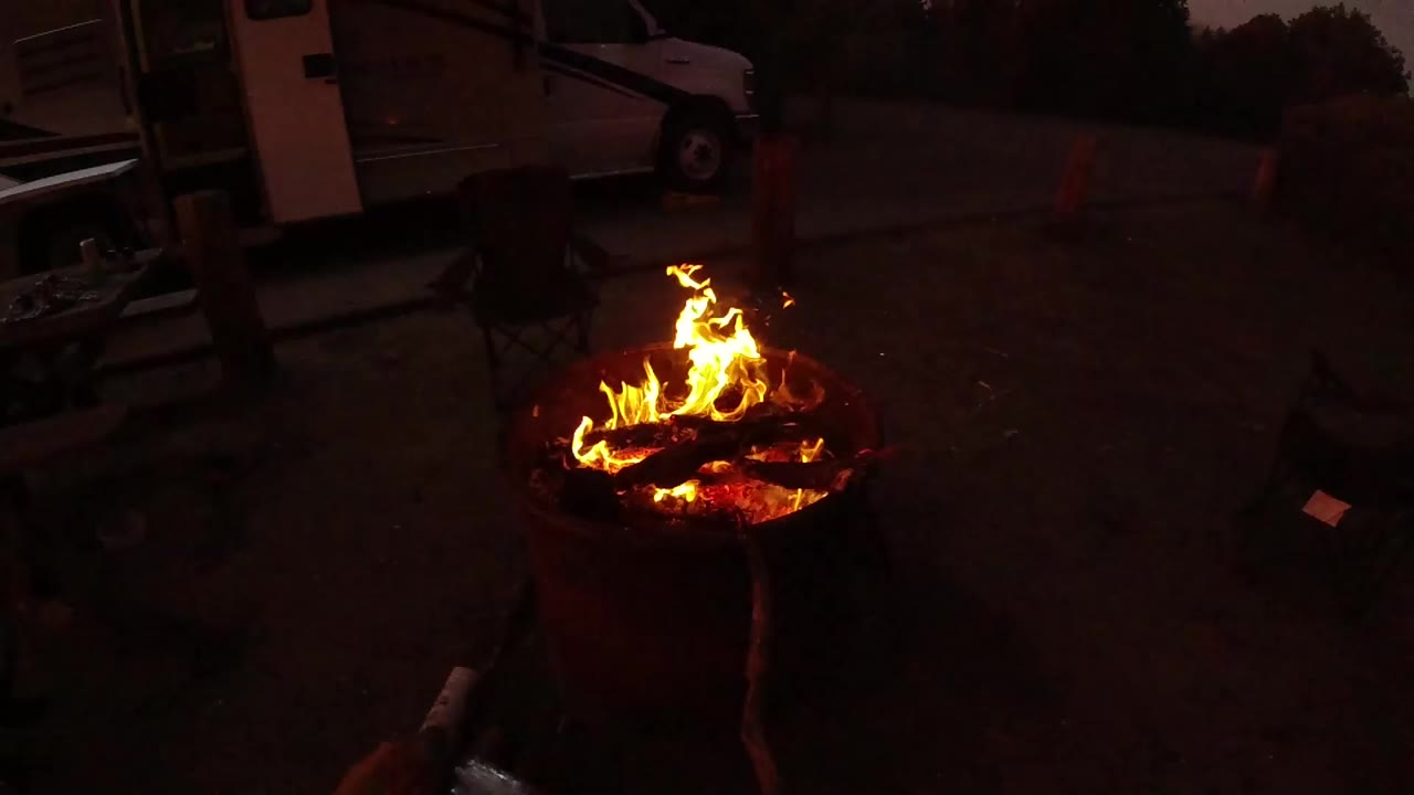 Flames burning in a round fire pit on a dark patio.
