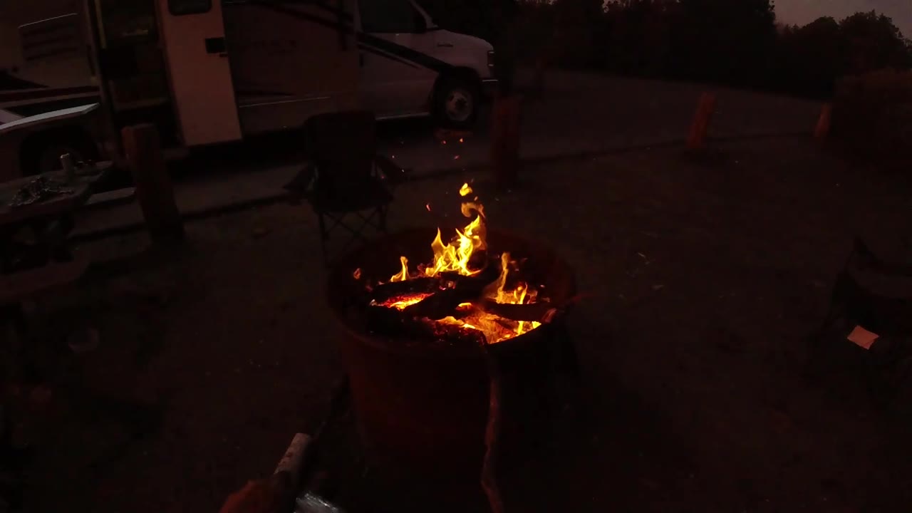 Lower flames in a burn barrel at dusk.